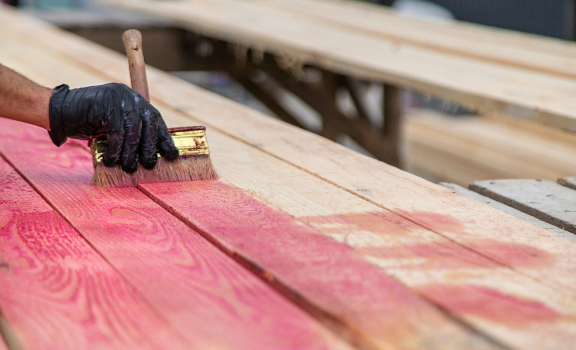 A man treats a board with a red antiseptic. selective focus.